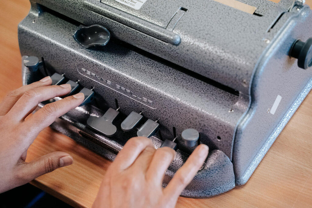 A close up shot of a ladies hands on a Perkins Braille machine
